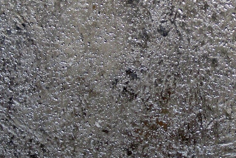 Close-up of a cast silver bar with dips, ripples, and satin frost finish showing silver commodity